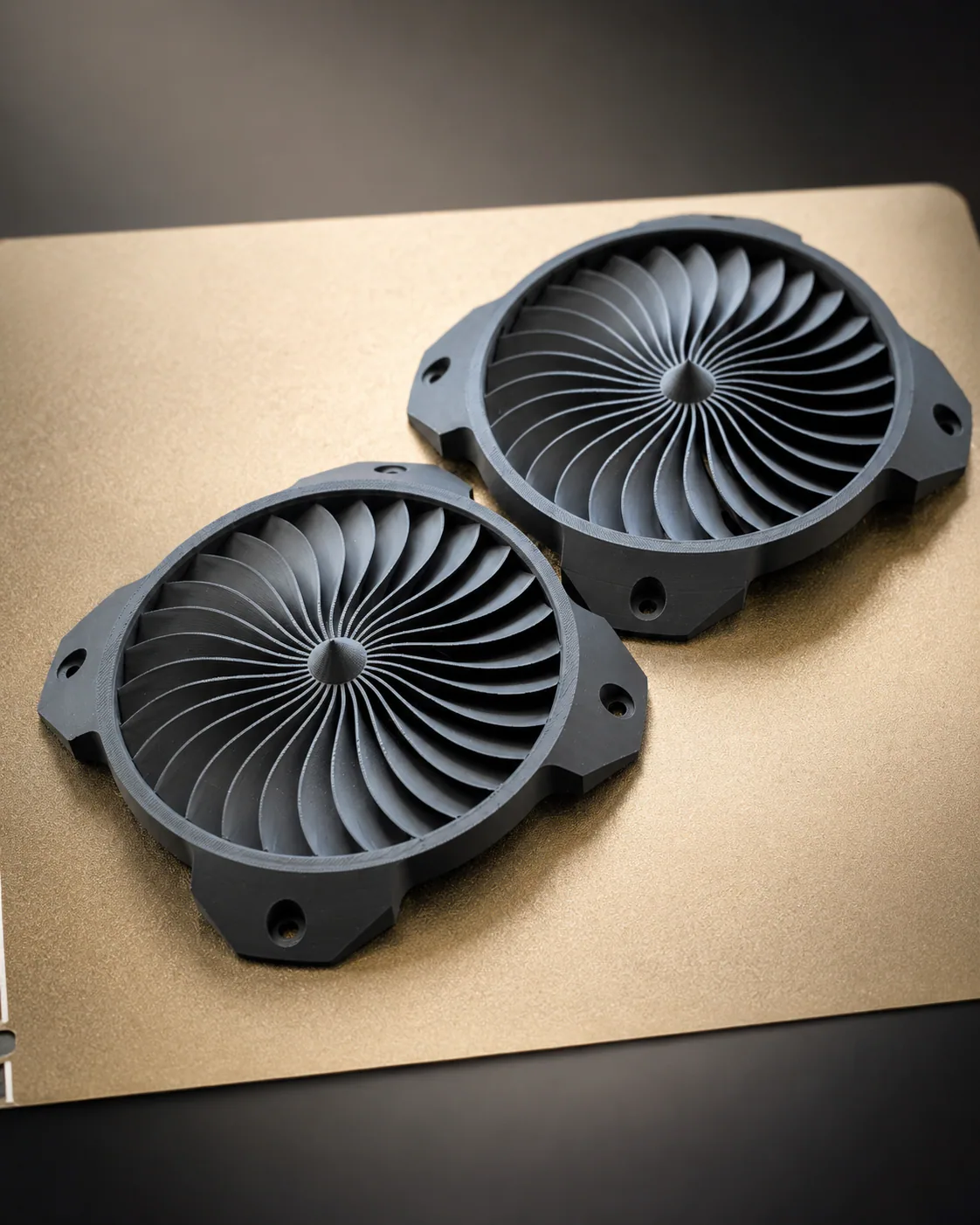 Pair of matching black 3D printed circular components with curved radial vanes